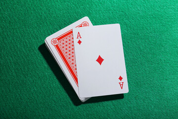Playing cards and ace of diamonds on green table, top view