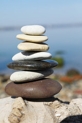Fototapeta na wymiar Stack of stones on rock near sea. Harmony and balance concept