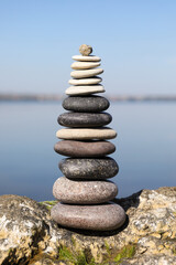 Fototapeta na wymiar Stack of stones on rock near sea. Harmony and balance concept