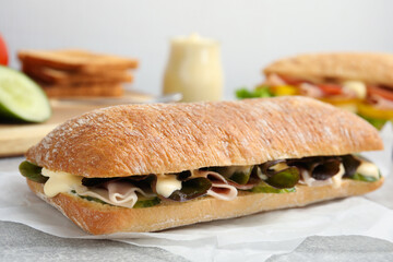 Delicious sandwich with vegetables, ham and mayonnaise on grey table, closeup
