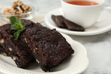 Delicious brownies with nuts and mint on white table, closeup. Space for text
