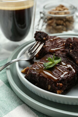 Delicious chocolate brownies with nuts, caramel sauce and fresh mint on napkin, closeup