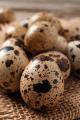 Obraz premium Fresh quail eggs on burlap fabric, closeup
