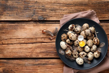 Plate with quail eggs on wooden table, top view. Space for text