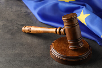 Wooden judge's gavel and flag of European Union on grey table. Space for text
