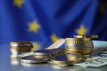 Coins and banknotes on table against European Union flag, closeup. Space for text - obrazy, fototapety, plakaty