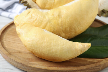 Pieces of fresh ripe durian on wooden plate, closeup
