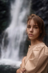 Portrait of a beautiful brunette girl on the background of a waterfall.