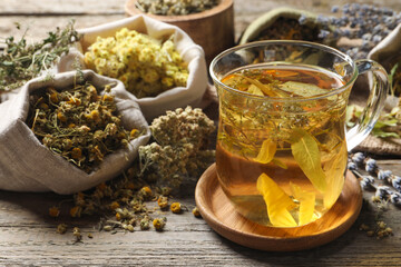 Freshly brewed tea and dried herbs on wooden table