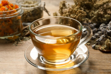 Freshly brewed tea and dried herbs on wooden table