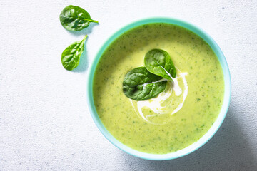 Green soup. Zucchini, spinach cream soup with cream. Healthy vegan dish. Top view at white table.