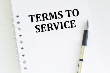 Terms to service text on notepad next to pen on light desk, business concept