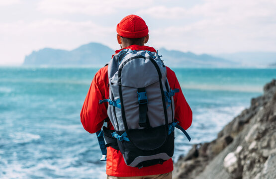 Tourist with a backpack on the background of the sea, rear view. A man in tourist gear on the background of the sea. The concept of travel and an active lifestyle. Copy space