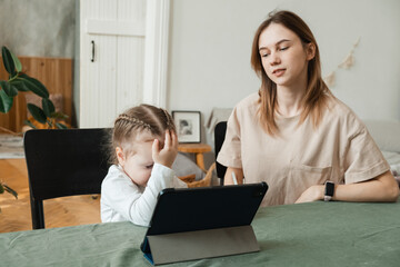 The little girl does not understand how to do homework or solve a problem. Stressed mother homeschooling with her child during coronavirus, Covid-19 outbreak quarantine. Self isolation, social