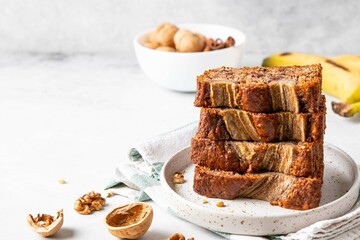 Pieces of american homemade sliced banana bread with chopped walnuts, chocolate chips and cinnamon. Stack of pieces of bread. Breakfast concept. Selective focus. Copy space for text.