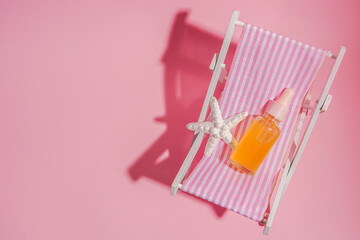 Essential oil into bottleon the sunbed with shadow on pink background, copy space