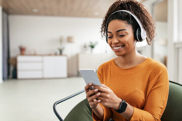Smiling black lady in headhones using cell phone
