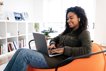 Portrait of smiling black woman using laptop at home