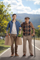 Young man helping a senior outdoors and carrying groceries