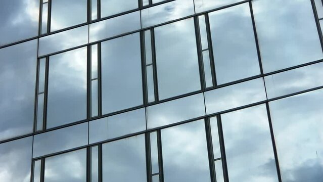 Time lapse of a blue summer sky with clouds reflecting off the glass facade of an office building