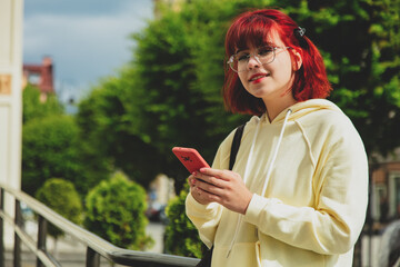 Young redhead ukrainian teen girl with mobile phone on city street