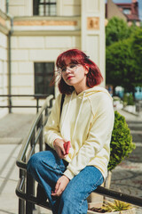 Obraz na płótnie Canvas Young redhead ukrainian teen girl with mobile phone sit on rails on city street