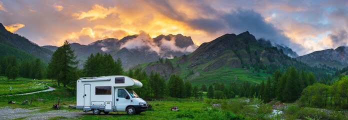 Camper van in the mountains, the Alps, Piedmont, Italy. Sunset dramatic sky and clouds, unique...