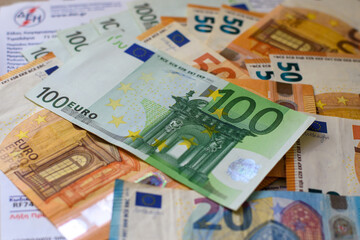 Close up of Euro money cash in 20, 50, 100 banknotes on the Greek electricity bills. Selective focus