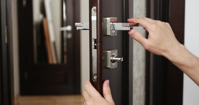 a man repairing a door knob. locksmith fixing a wooden door.