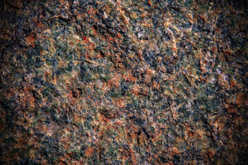 Multicolored granite texture with dark vignette. Stone background with copy space for design.