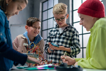 Group of kids working together on project with electric toys and robots at robotics classroom