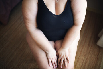 Midsection of fat woman in underwear sitting.