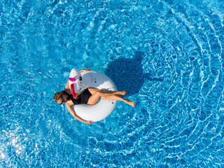 Aerial top view from drone of beach vacation woman relaxing in pool float unicorn inflatable ring...