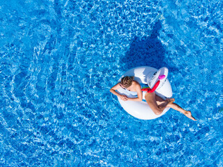 Woman on unicorn pool float in pool in hotel. Summer holidays, enjoying summer vacations during quarantine.