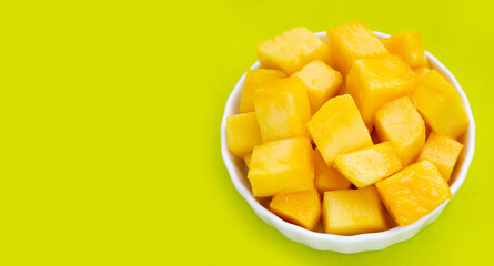 Yellow mango slices on green background.