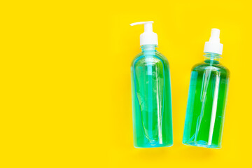Alcohol liquid gel sanitizer and spray on yellow background.
