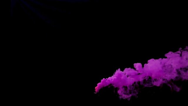 Colorful pink smoke bomb or haze grenade blowing across screen for festival or celebrations on black background.