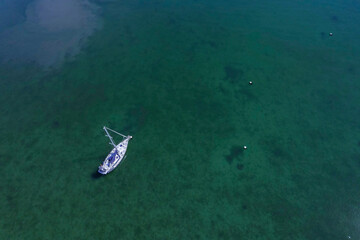 Aerial view on a white yacht in a calm ocean. Travel and tourism concept. Expensive hobby and sport.