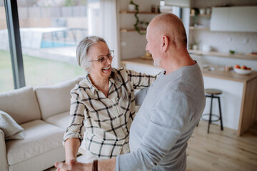 Cheerful senior couple dancing together at home.