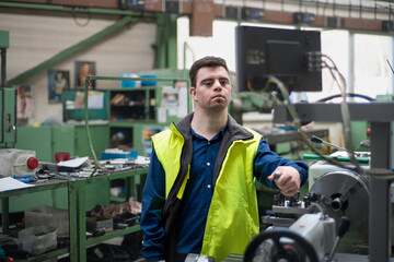 Young man with Down syndrome working in industrial factory, social integration concept.