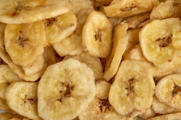Banana chips background top view. Dried banana slices texture. Heap of dried bananas.
