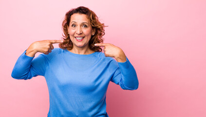 middle age hispanic woman smiling confidently pointing to own broad smile, positive, relaxed,...