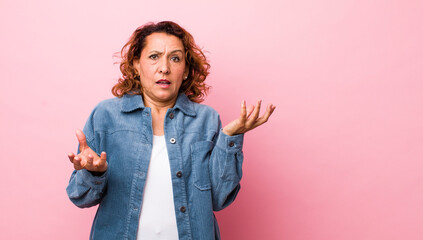 middle age hispanic woman shrugging with a dumb, crazy, confused, puzzled expression, feeling...