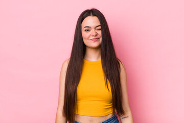 young adult woman looking happy and friendly, smiling and winking an eye at you with a positive...