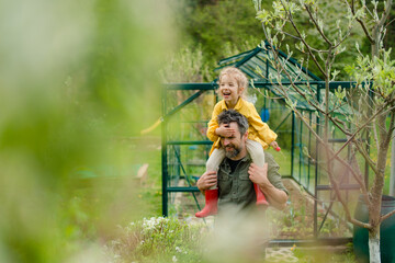 Father with his little daughter bonding in front of eco greenhouse, sustainable lifestyle.