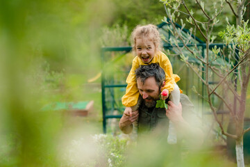 Father with his little daughter bonding in front of eco greenhouse, sustainable lifestyle.