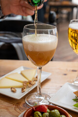 Lunch with cold beer in Spanish outdoor cafe, tapas bowl with green olives and Spanish cheese manchego with nuts