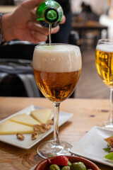 Lunch with cold beer in Spanish outdoor cafe, tapas bowl with green olives and Spanish cheese manchego with nuts