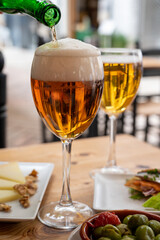Lunch with cold beer in Spanish outdoor cafe, tapas bowl with green olives and Spanish cheese manchego with nuts