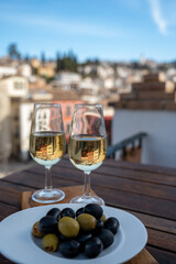 Tasting of Spanish sweet and dry fortified Vino de Jerez sherry wine and olives with view on roofs and houses of old andalusian town